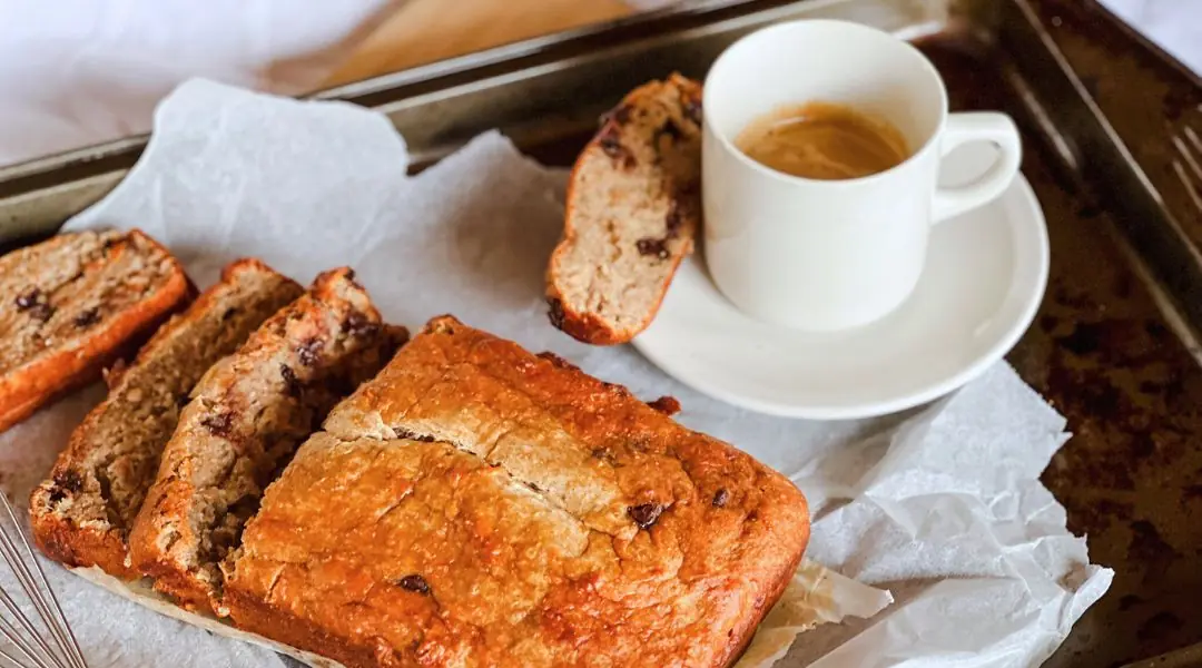 Tranches de pain aux bananes maison avec pépites de chocolat, servies sur un plateau avec une tasse d’espresso