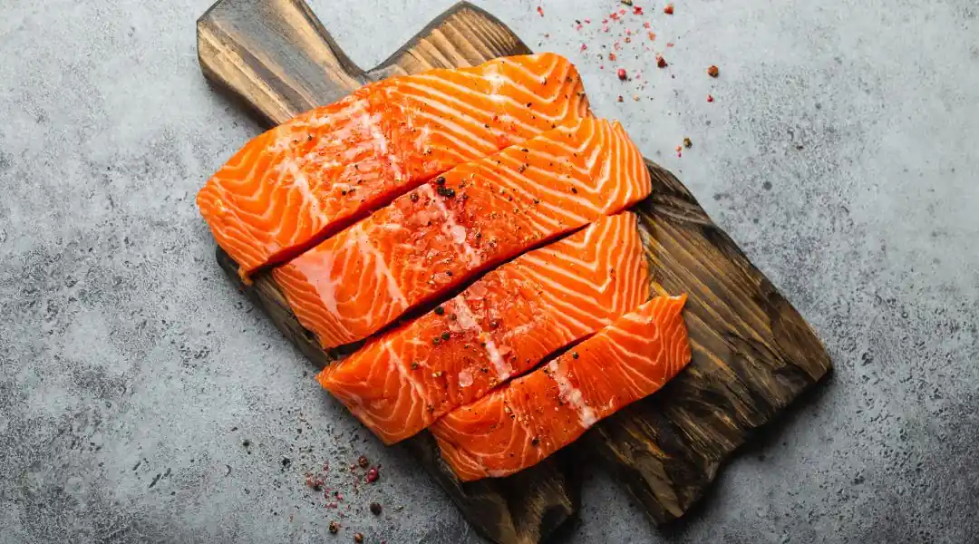 Filets de saumon cru sur une planche rustique avec sel de mer et poivre
