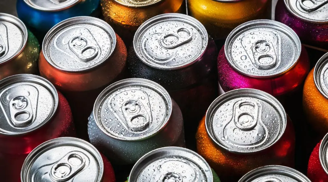 Gros plan sur des canettes de boisson gazeuse colorées avec des gouttelettes d'eau, empilées ensemble