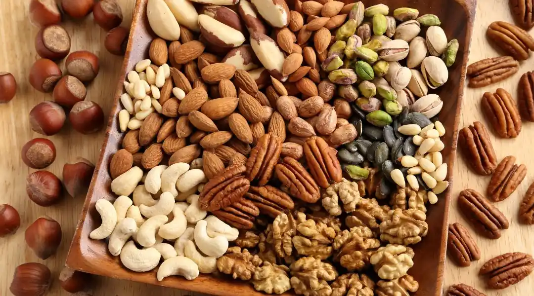 Assortiment de noix incluant amandes, noix, cajous et pistaches dans un plateau en bois