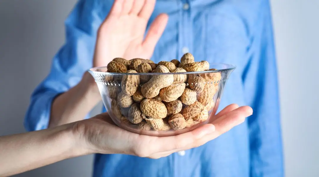 Main refusant un bol de cacahuètes, geste d’allergie ou d’aversion
