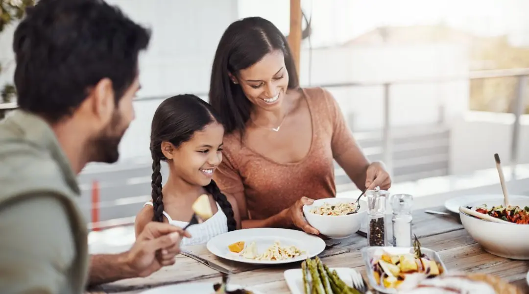 Famille souriante partageant un repas de pâtes en plein air