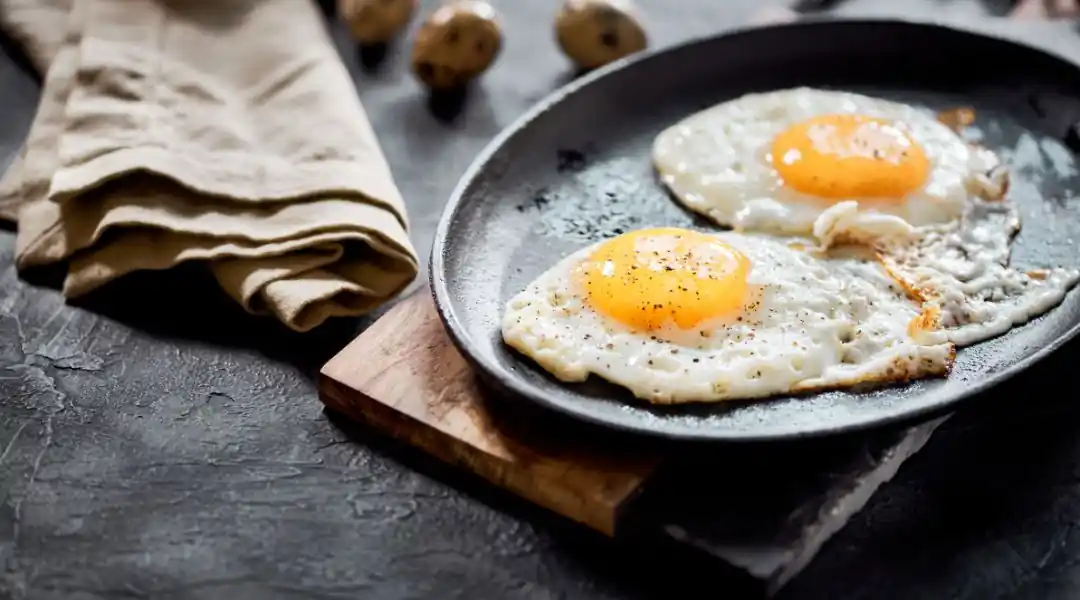 Deux œufs au plat assaisonnés de poivre noir dans une poêle
