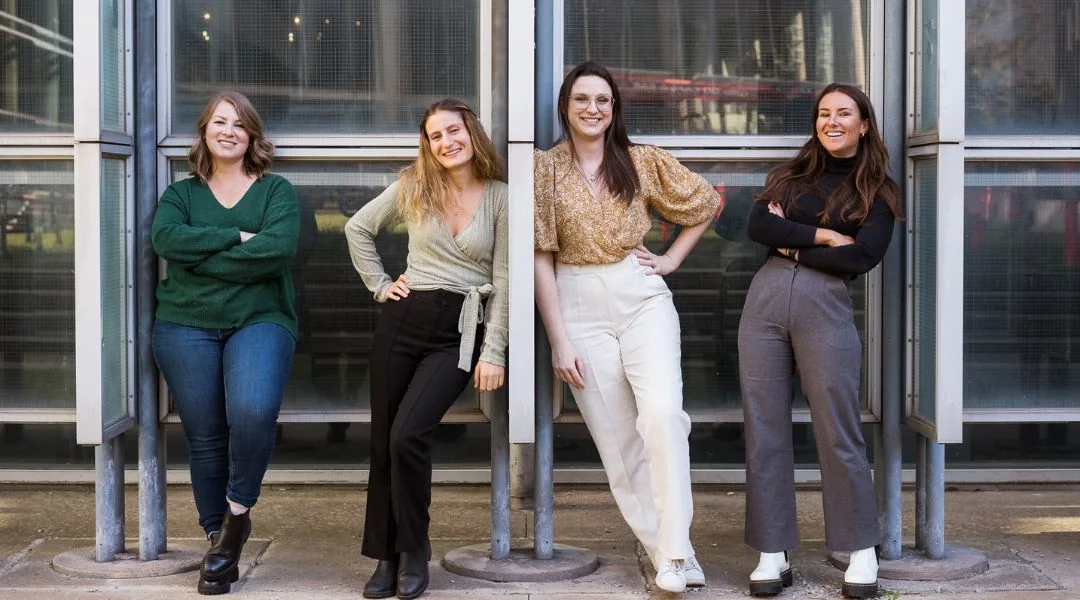 Équipe de quatre nutritionnistes diététistes posant devant un bâtiment moderne