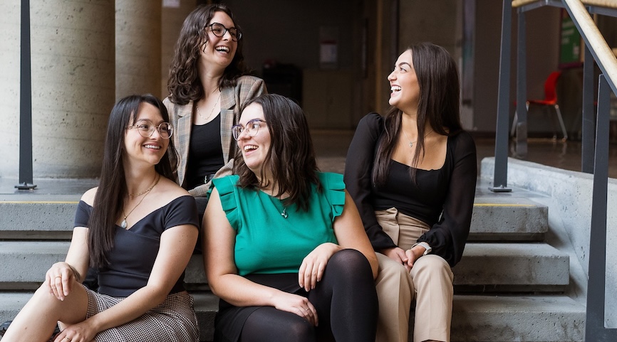 Quatre femmes nutritionnistes assises sur des escaliers, souriant et riant ensemble dans une ambiance décontractée et conviviale.