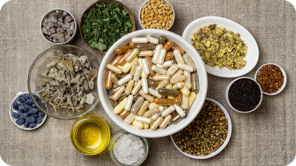 Suppléments alimentaires dans un bol entourés d'ingrédients naturels et d'herbes