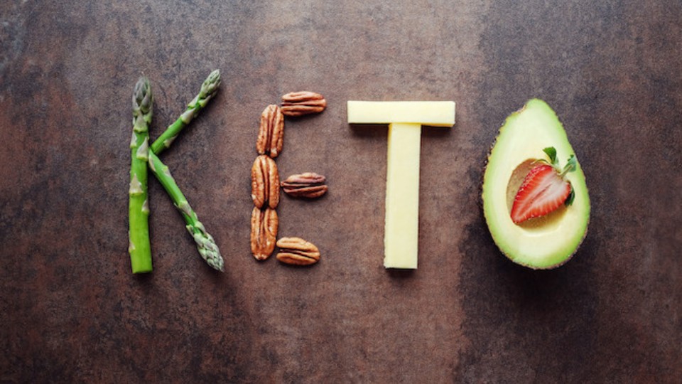 Keto écrit sur un fond de bois avec des légumes et des protéines