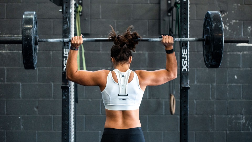 femme de dos musclée qui lève un haltère