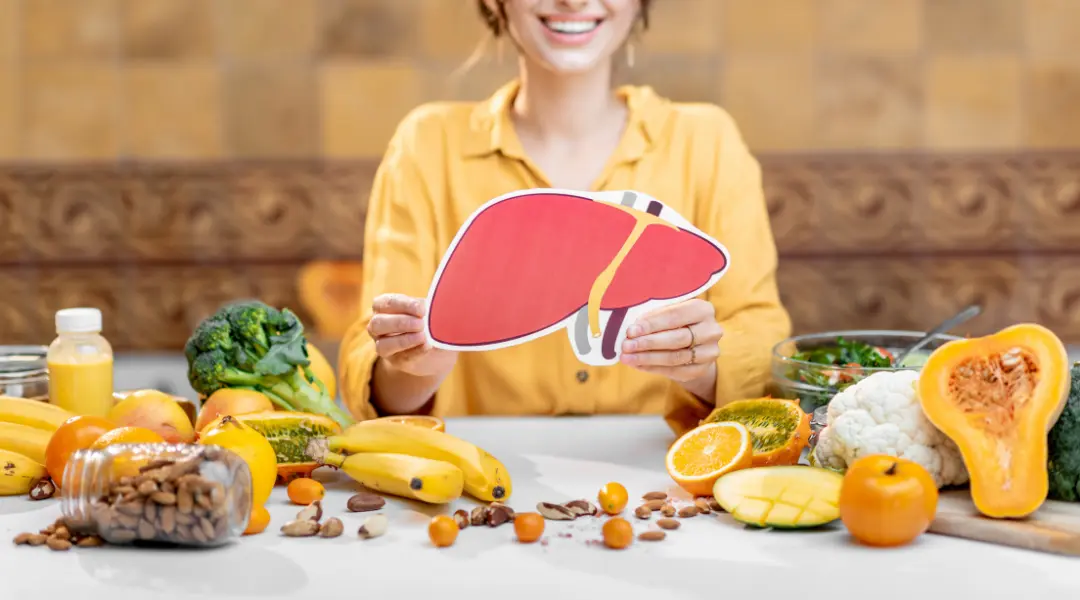 A person holding up a liver surrounded by fruits and vegetables. Nutritionnistes : acteurs clés de la  gestion de la stéatose hépatique métabolique