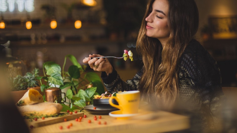 A woman drinking her hot tea while working outside in front of her computer.