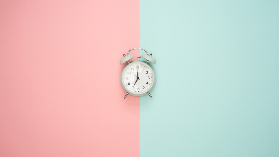 horloge au centre d'un fond moitié rose et moitié turquoise