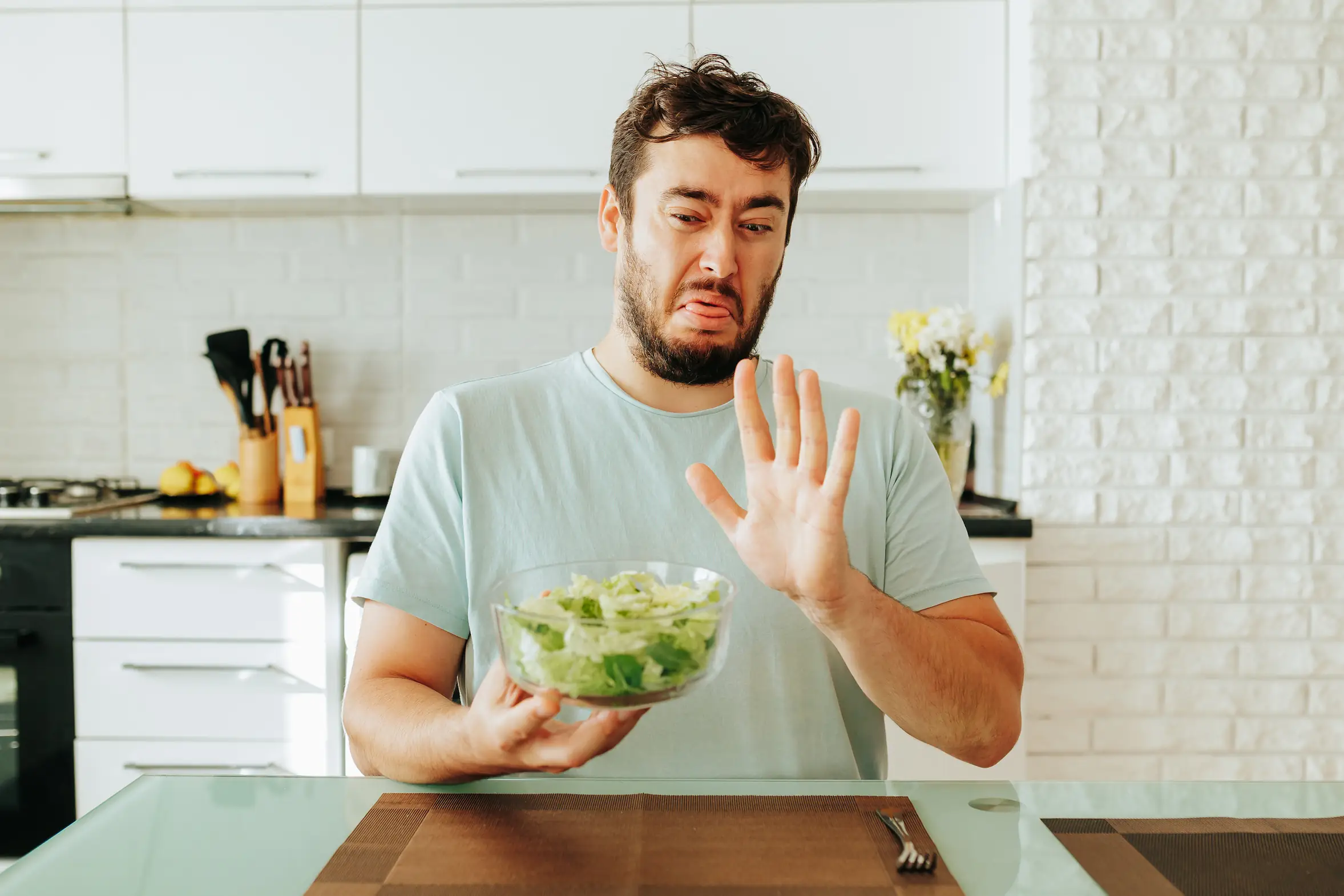 Homme faisant la grimace en tenant un bol de salade - Man grimacing while holding a bowl of salad