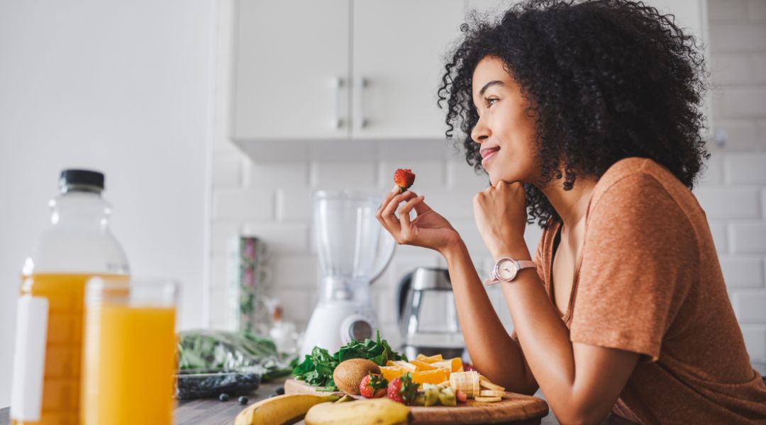 femme dans sa cuisine qui mange une fraise