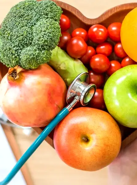 Triglycérides : des gestes concrets pour un taux plus sain. a person holding a stethoscope next to a bowl of fruits and vegetables