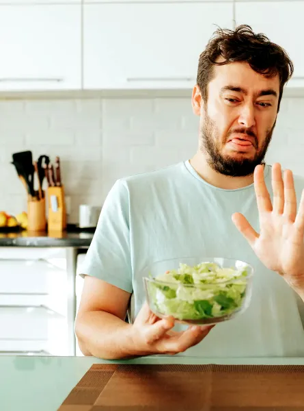 Homme faisant la grimace en tenant un bol de salade - Man grimacing while holding a bowl of salad