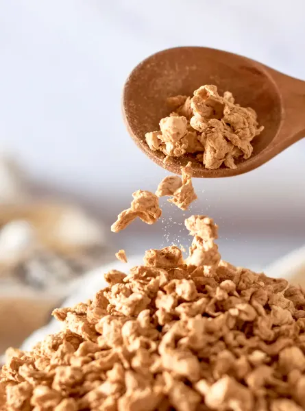 Cuillère en bois versant des protéines végétales texturées séchées - Wooden spoon pouring dried textured vegetable protein
